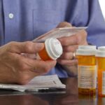 Person holding a prescription bottle and reading medical instructions