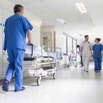 Susan Fuhrmann walking with a nurse in a bright hospital corridor