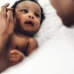 Baby Dies – Murder Charge Quietly Evaporates Baby lying on a bed looking up at an adult