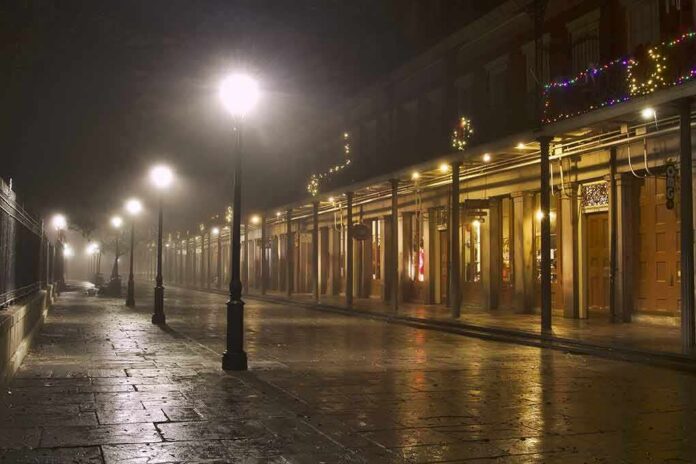Foggy street with lit lampposts and decorated storefronts at night
