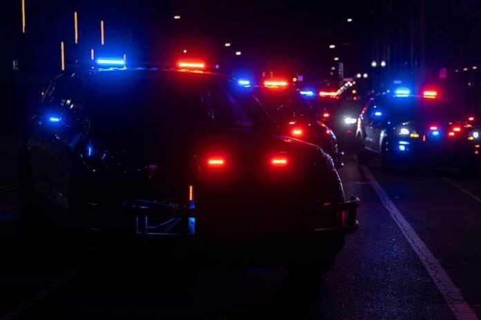 shutterstock_2304512557-1 Police vehicles with flashing red and blue lights at night