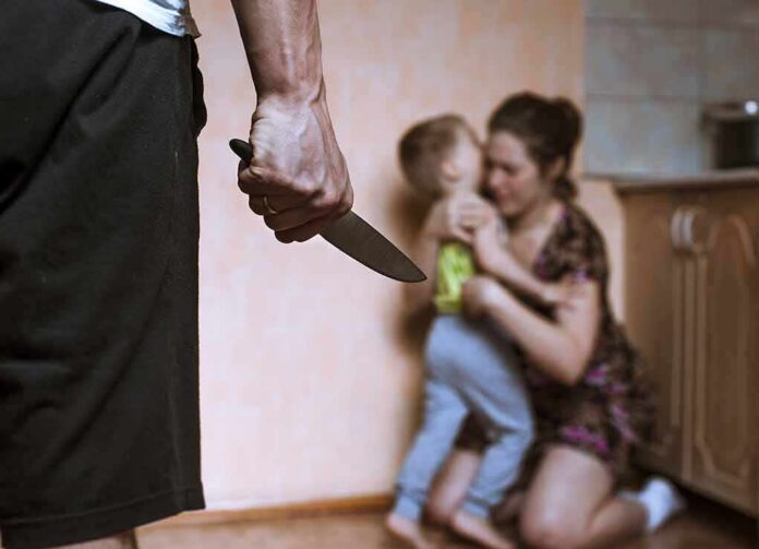 Man holding knife as woman shields child in kitchen