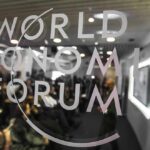 World Economic Forum logo on glass with audience blurred behind