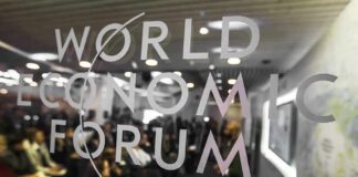 World Economic Forum logo on glass with audience blurred behind