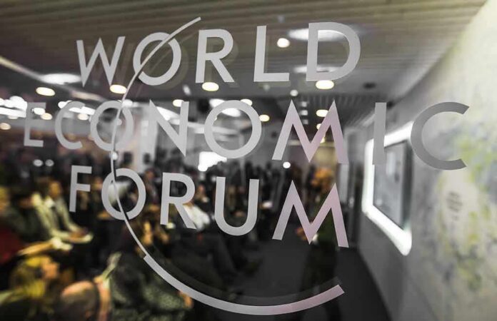 World Economic Forum logo on glass with audience blurred behind