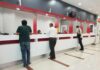 People at numbered service counters in a modern lobby