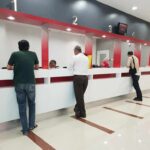 People at numbered service counters in a modern lobby
