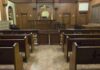 Interior view of an empty courtroom with wooden benches and a judges bench