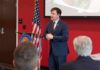 Speaker in a navy suit addressing an audience at a podium