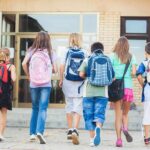 Backpack Bomb Horror On School Hike Group of children walking towards a school entrance with backpacks