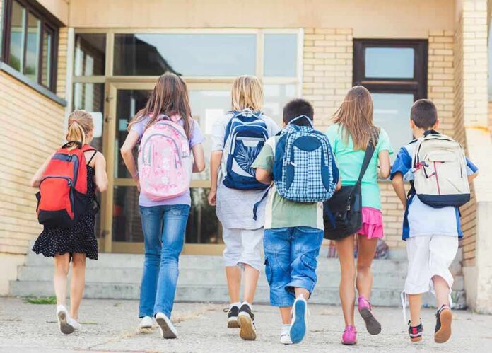 shutterstock_167557547 Group of children walking towards a school entrance with backpacks