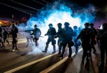 Paris Crackdown Ignites Rights Showdown Riot police advance through tear gas at night on a city street