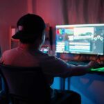 Person editing video at dual-monitor PC with RGB lights