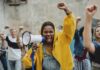 Protester in yellow hoodie shouting into a megaphone