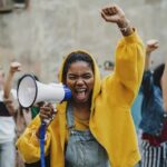 Protester in yellow hoodie shouting into a megaphone