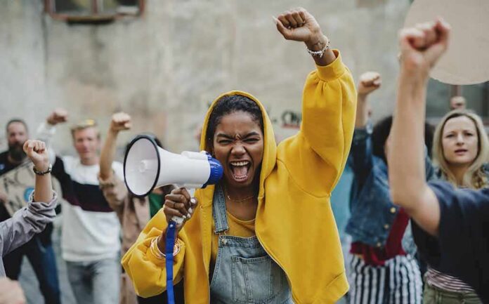 Protester in yellow hoodie shouting into a megaphone