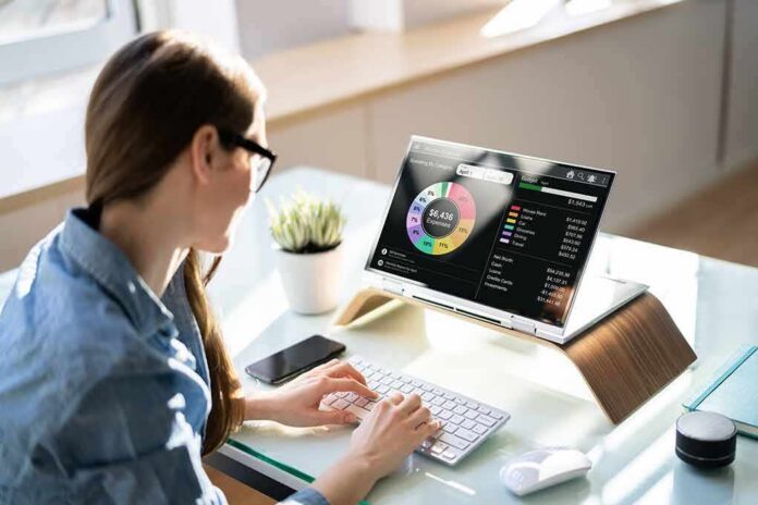 Woman working at desk with laptop showing finance dashboard