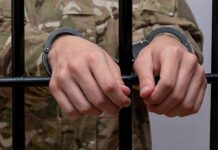 Hands in handcuffs gripping jail bars