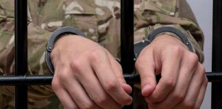 Hands in handcuffs gripping jail bars