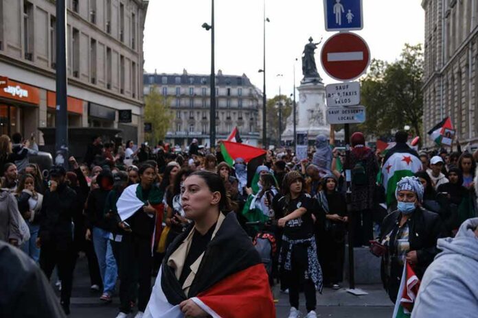 Brian Folkerts and Ricardo Santos at a street protest with flags and a large crowd
