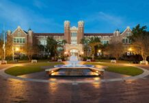 Historic brick university building with central fountain at dusk