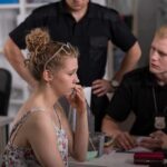 Young woman speaking with two officers at a desk