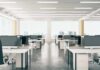 Open-plan office with rows of desks and monitors