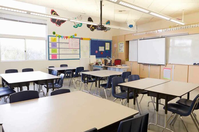 shutterstock_388578202-1 Empty classroom with tables, chairs, and a whiteboard