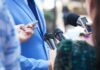 Reporters hold microphones toward a person in a blue suit